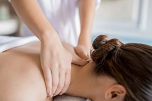 Hands of masseuse massaging neck and shoulders of relaxed client